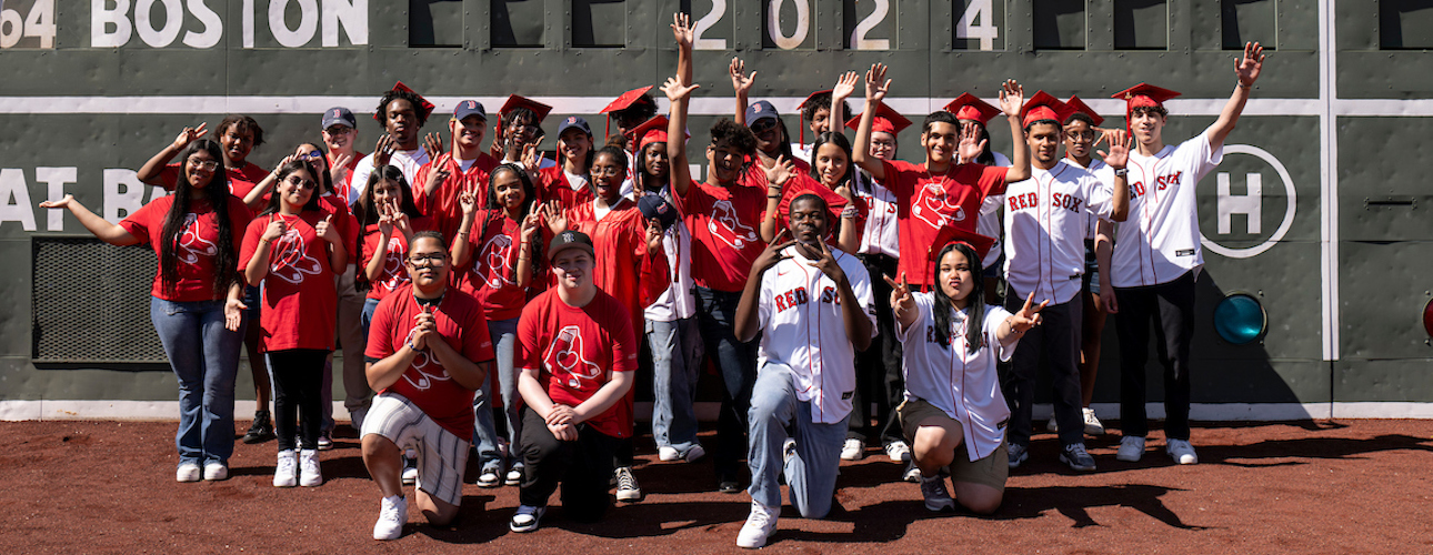 Red Sox Scholars celebrating in front of the Green Monster at Fenway Park